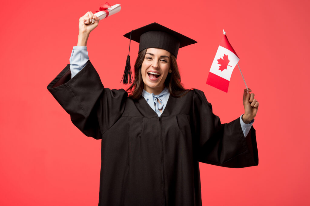 Aluna em acadêmico vestido segurando a bandeira canadense e diploma em fundo coral.