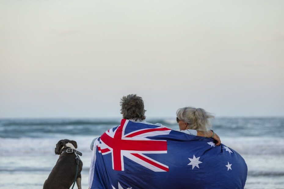 Imagem de casal com cachorro envolto em bandeira para ilustrar conteúdo sobre intercâmbio na Austrália.