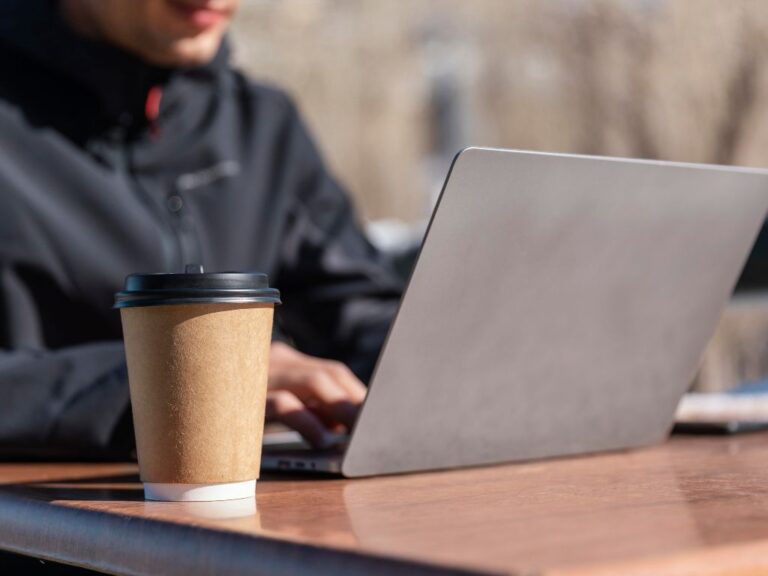 Imagem de uma pessoa com notebook na cafeteria para ilustrar conteúdo sobre visto para nômades digitais.